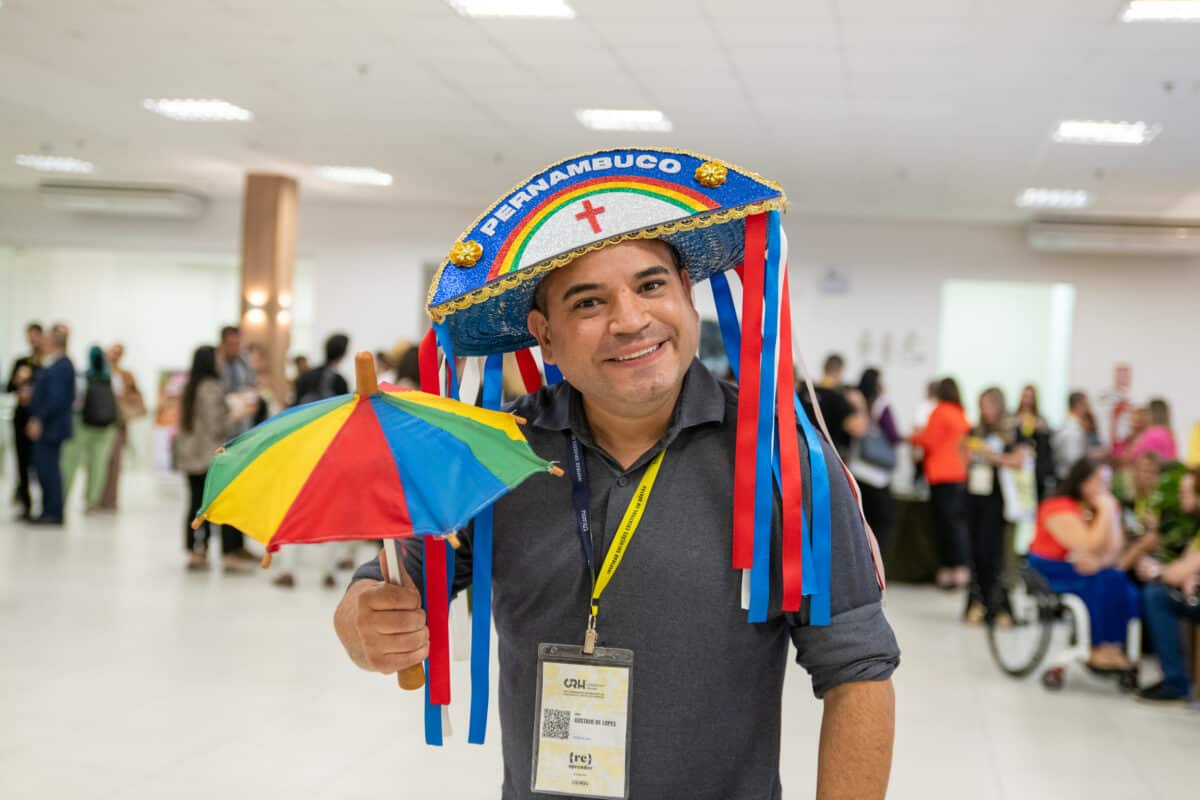 Um homem usando um chapéu vibrante enquanto segura um guarda-chuva.