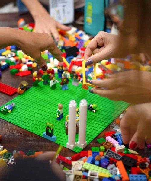 Um grupo de pessoas brincando com legos sobre uma mesa.